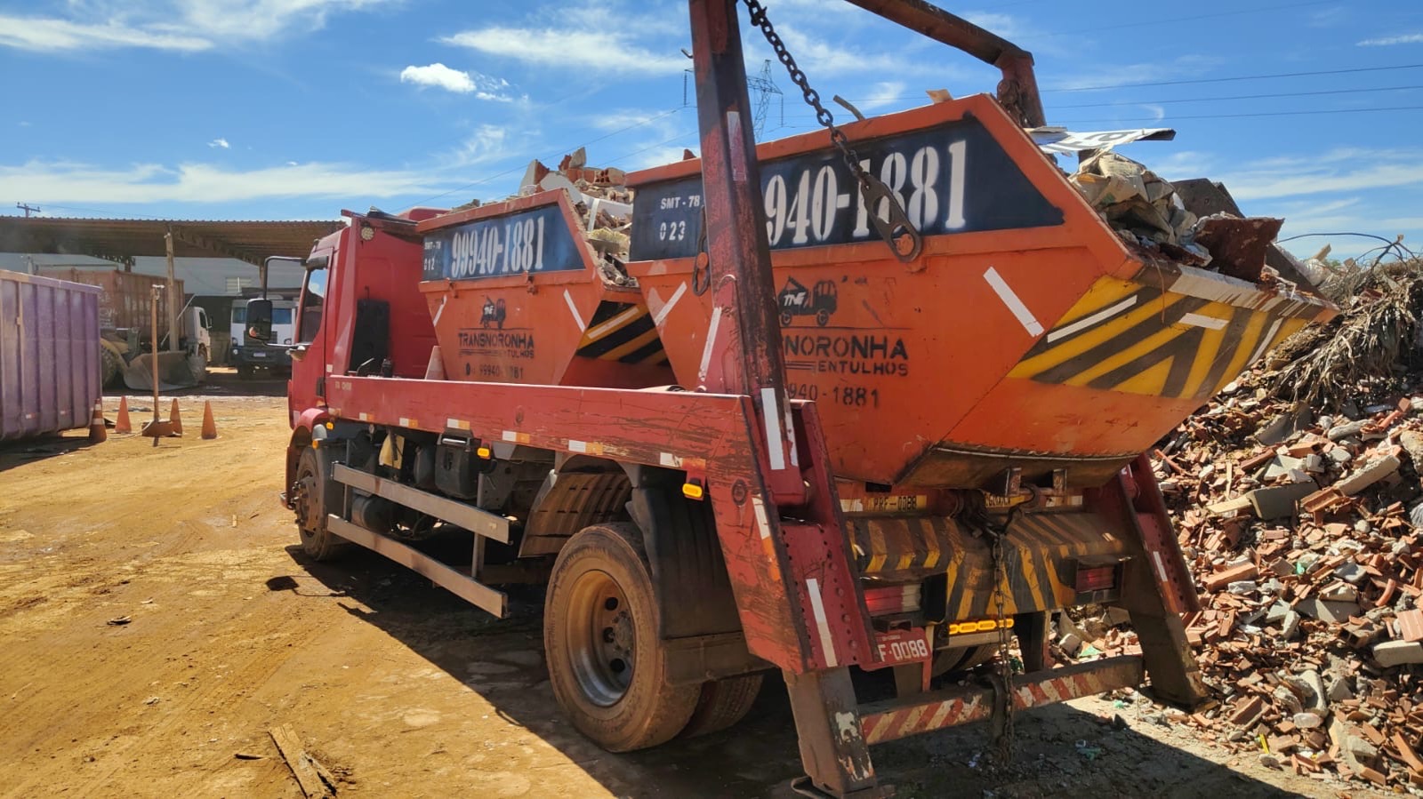 Caminhão da Transnoronha descarregando uma caçamba de entulho no pátio de transbordo da empresa